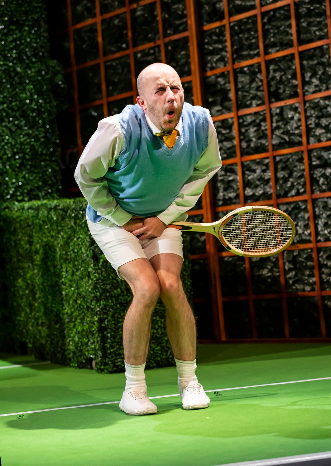 A male character holding a tennis racket is in pain after being hit between the legs.