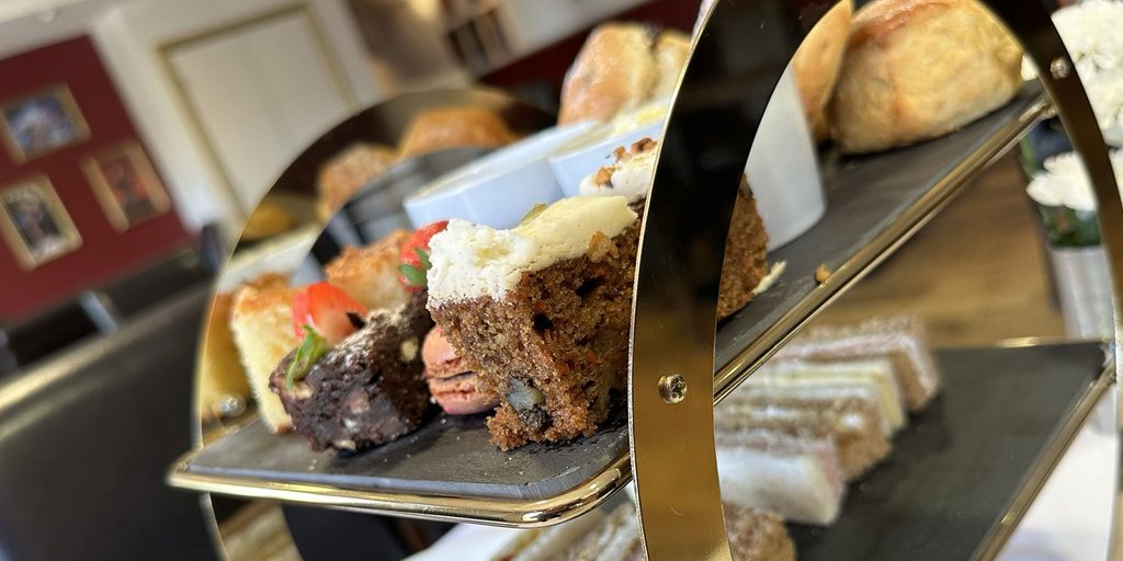 Cakes, scones and finger sandwiches displayed on a 2 layered tray