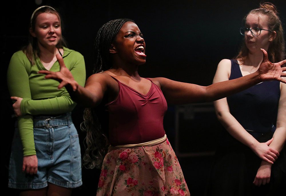 Young woman sings with arms wide open