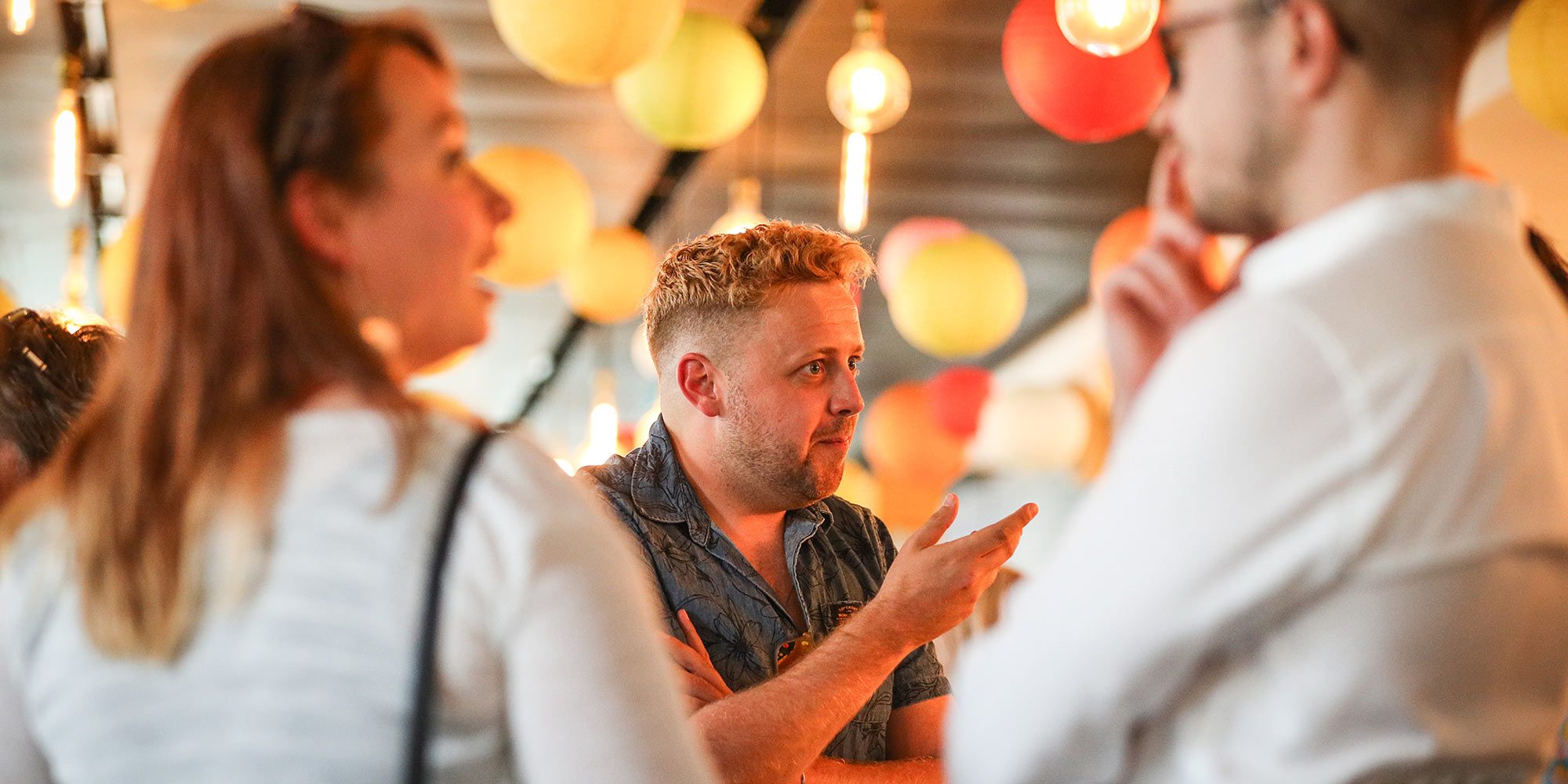 A group of 3 adults are stood in the cafe at MAST Mayflower Studios whilst in deep discussion and talking animatedly.