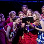 A group of young white females reading from a book during a scene from Guys and Dolls