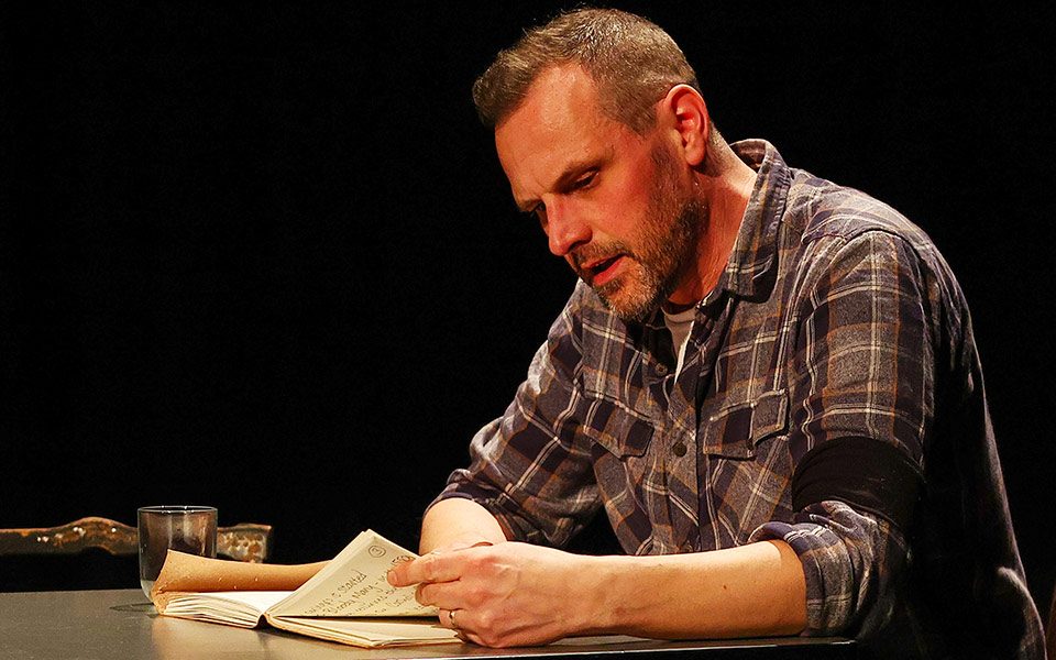 Middle-aged white man sat on a chair at a table studying some documents