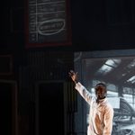 One male character wearing a lab coat and bow tie points upwards at a blackboard.