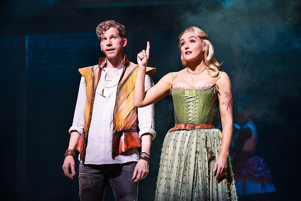 Anne Hathaway holds her finger up as William Shakespeare starts to speak