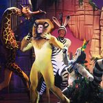 Man dressed as lion looks up at person dressed as giraffe as man-zebra and man-lemur look on