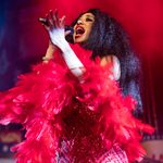 Black woman in red dress and feather boa singing