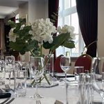 A long table with glasses, cutlery and white and red chairs