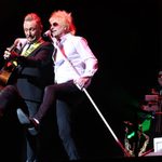 Rod Stewart impersonator and male acoustic guitarist kick their legs up together