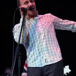 Steve Ellis singing into microphone, wearing white checked shirt