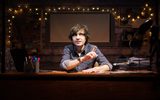 Danny Robins sits at desk pointing as though holding a thought